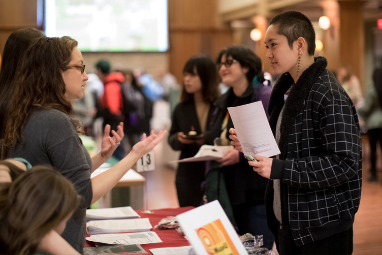 People speaking at tables while holding flyers