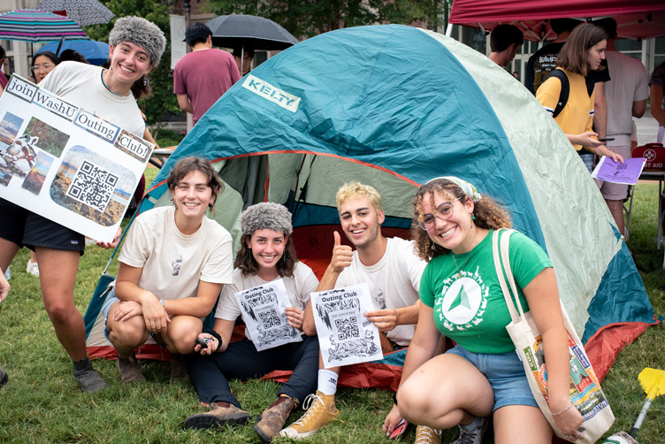 Students sit near tent at Activities Fair to promote the Outing Club