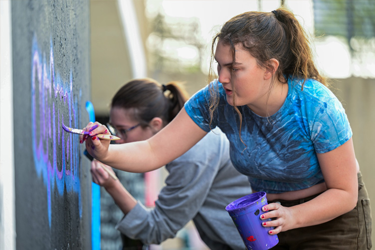 two students paint the underpass