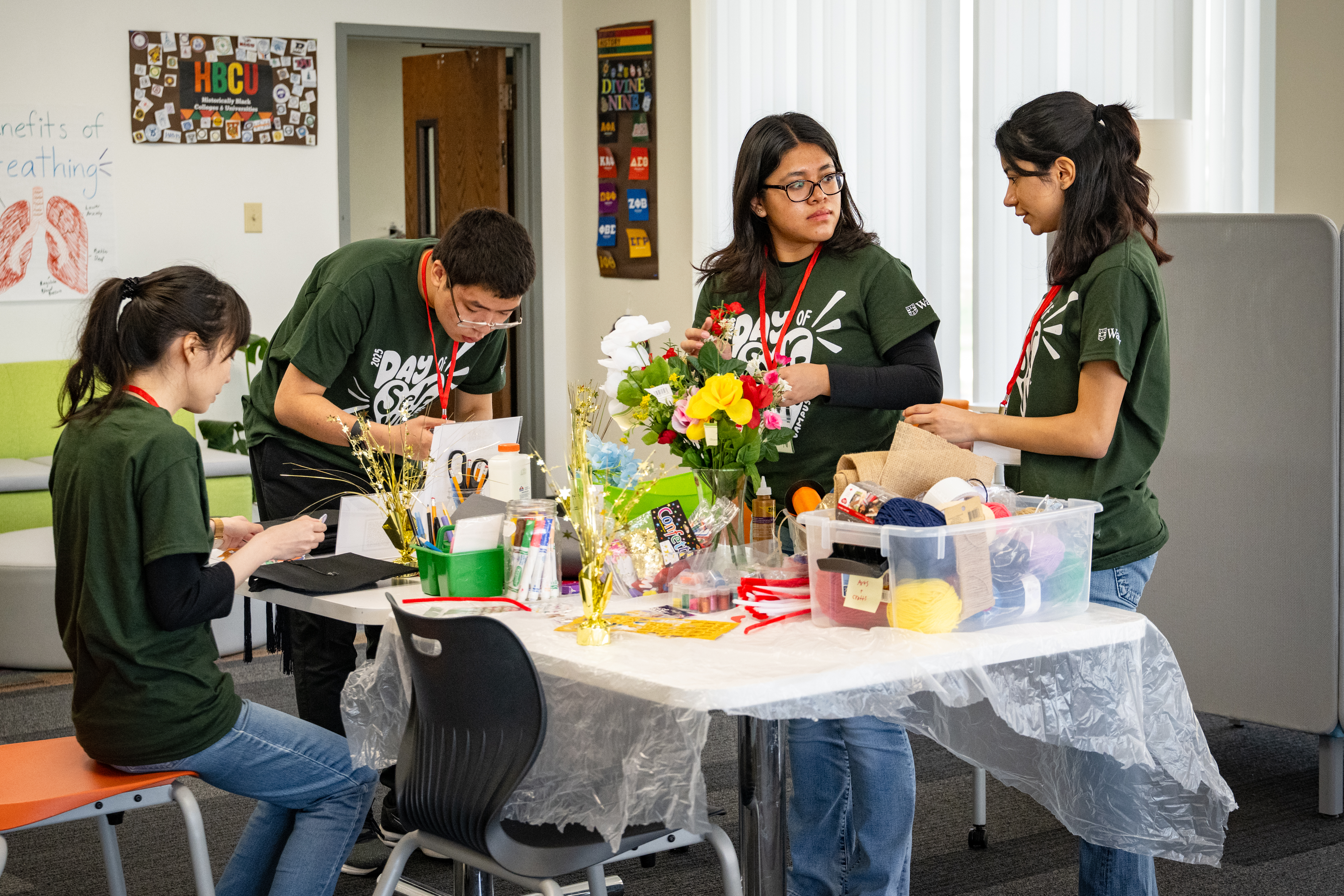 Students in matching Day of Service shirts prepare floral center pieces